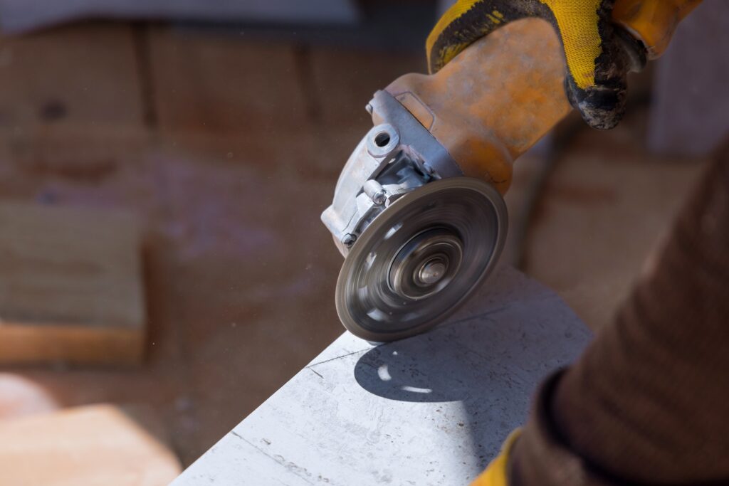 The worker cuts the tiles with a special tool with a diamond disc